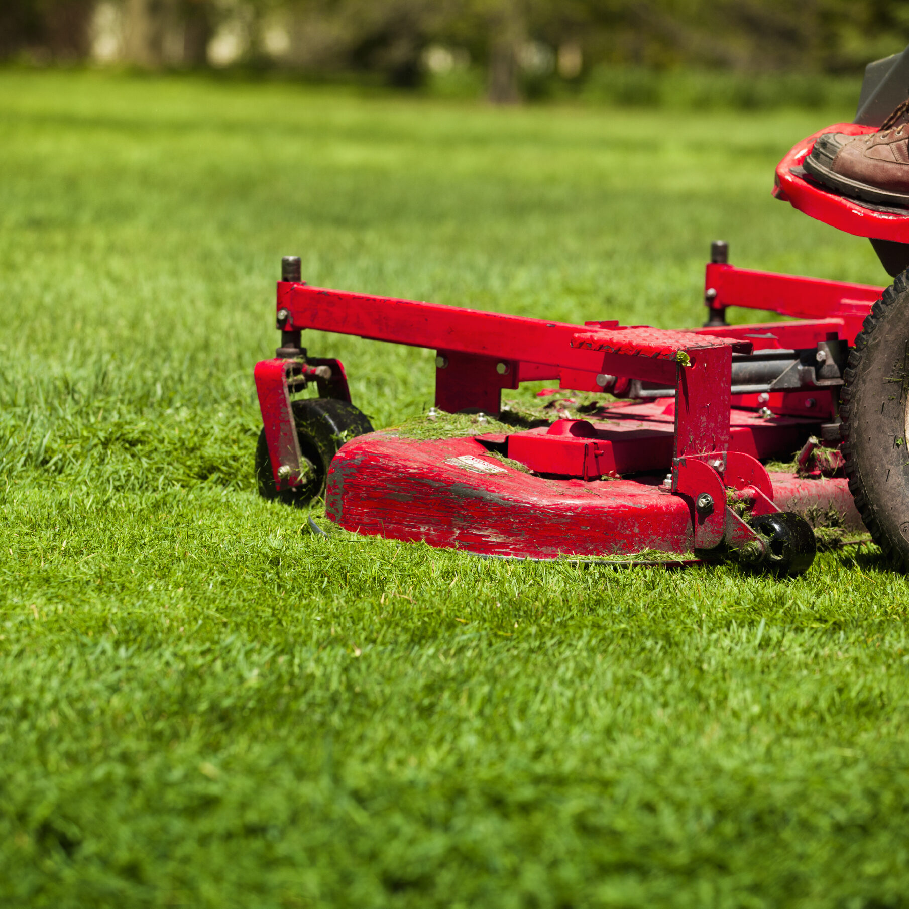 Gardener in the park on a lawn cutting tractor machine